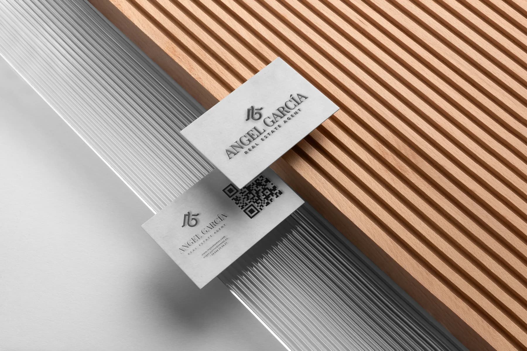 Angel Garcia real estate agent business card mockup on wood and glass surfaces.
